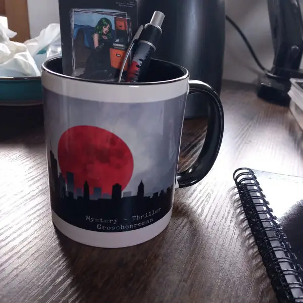 Kaffeetasse mit Loge "Hinter dem Schleier" Darin der dazugehörige Kuli und ein Lesezeichen.